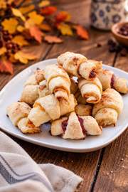Golden, crescent-shaped apricot rugelach pastries with a flaky, lightly browned crust and sweet apricot filling.