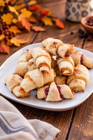 Golden, crescent-shaped apricot rugelach pastries with a flaky, lightly browned crust and sweet apricot filling.