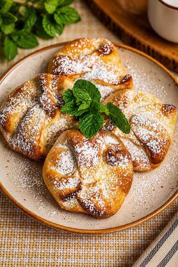 Traditional Romanian poale-n brâu pastries with golden-brown dough folded around a sweet cheese and raisin filling.